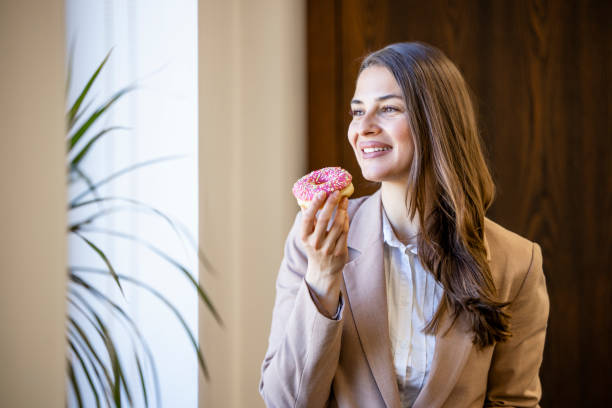 istock Beautiful woman eating donuts and drinking coffee at work. 1644981624