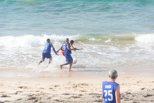 Salvador, Bahia, Brazil - February 20, 2022: People have fun playing beach soccer at Farol da Barra beach in the city of Salvador, Bahia.