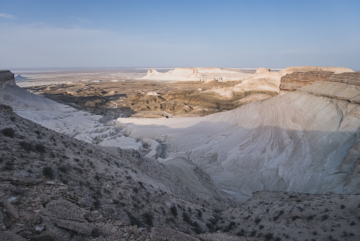 Panorama of hills and ridges with limestone and chalk slopes in the Kazakh steppe at dawn, relief folds in the desert tract of Boszhira in the evening at sunset