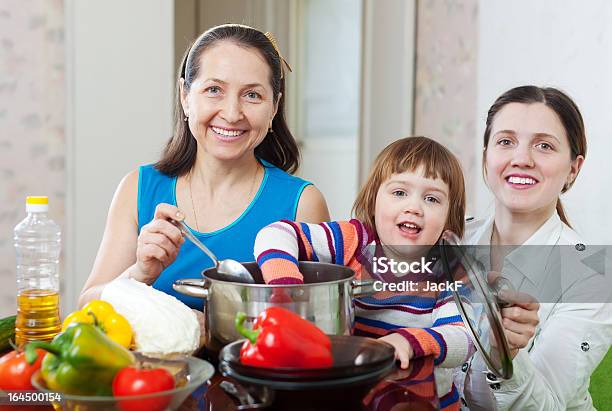 Donna Matura E Figlia Adulta Con Ragazza Cook Pranzo - Fotografie stock e altre immagini di 45-49 anni