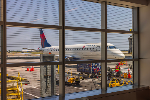 USA. NY. 08.28.2023. View of parked Delta aircraft from inside of airport through window.