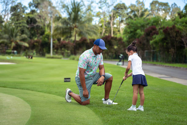 istock Young girl practices golf swing with the help of her father 1645031299
