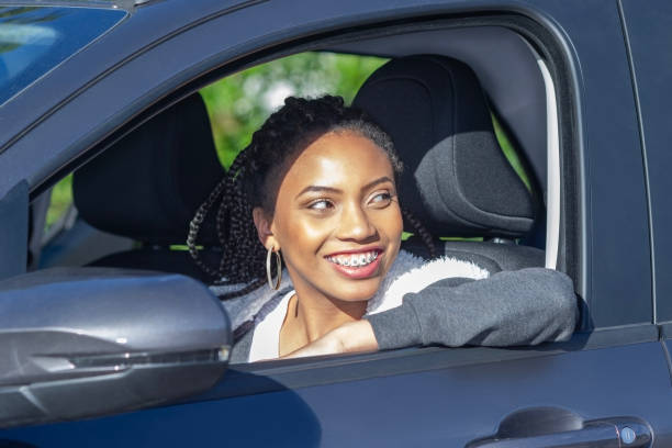 istock Young smiling black woman sitting in car, side view 1645049815