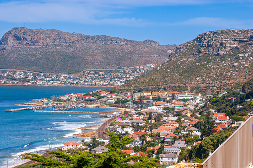 The coastal town of Simon's Town in the Cape Province of South Africa is home to South Africa's Navy. Photo shows houses and buildings by the sea. A railroad track can be seen winding through the buildings and adds to the composition. Photo shot in the afternoon sunlight; horizontal format. Shot at a focal length of 200 mm which compresses the scene and adds to the effect.
