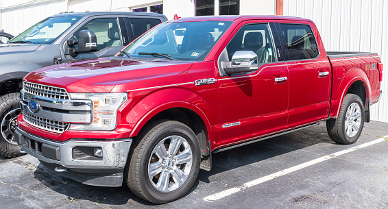 Warren, Pennsylvania, USA August 27, 2023 A new, four door red Ford F150 pickup truck for sale at a dealership on a sunny summer day