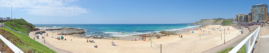 Wide angle view of Newcastle Beach and Canoe Pool in summer with the beach populated with beach goers.