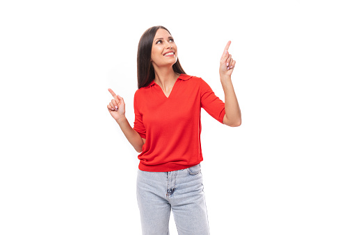 young inspired caucasian brunette woman in a red short sleeve shirt points with her hands to the sides.