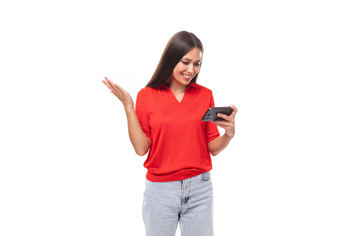 portrait of a cute young european brunette lady in a red t-shirt using online money transfers using a smartphone.