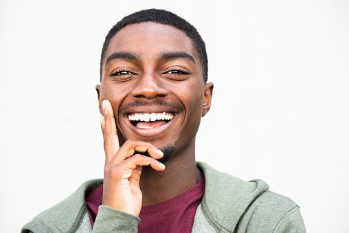 Close up portrait handsome young African American man smiling with thinking expression on face and hand to chin