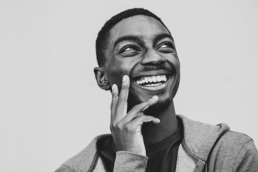 Black and white portrait young African American man laughing with hand to chin and looking away