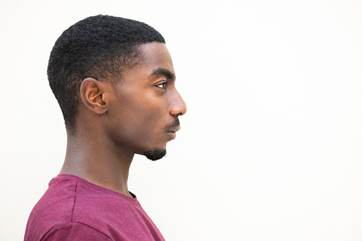 Close up profile portrait serious young african american man staring by isolated white background