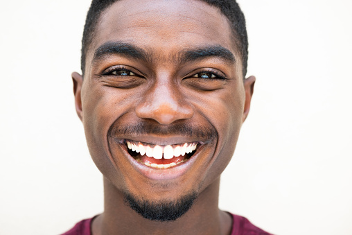 Close up portrait happy young african American man laughing against white background