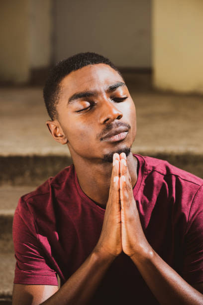 istock Close up portrait young black man with hands clasp in prayer 1645235777