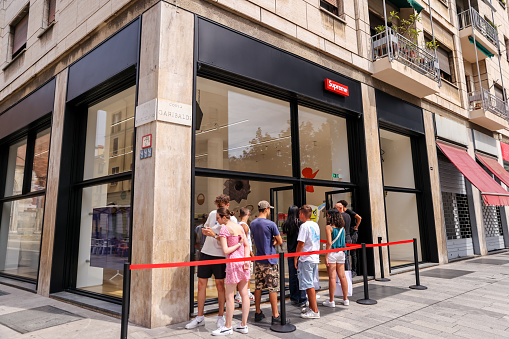 Milan, Italy - July 12, 2022: Customers lined up to enter the Supreme clothing and lifestyle store in Milan