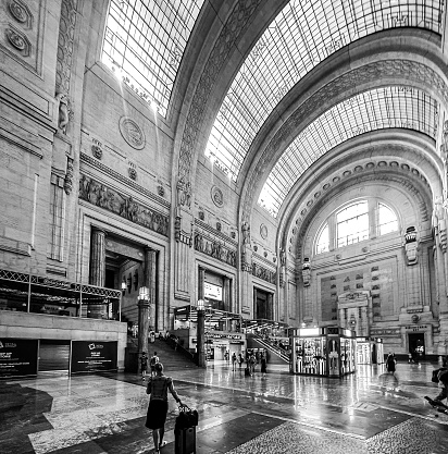 Milan, Italy - July 12, 2022: A woman pulling her luggage through the magestic central train station in Milan