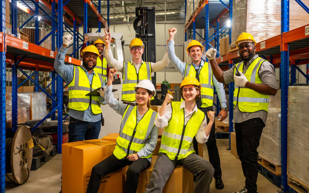 istock Group of happy warehouse workers celebrating success in warehouse 1645288018