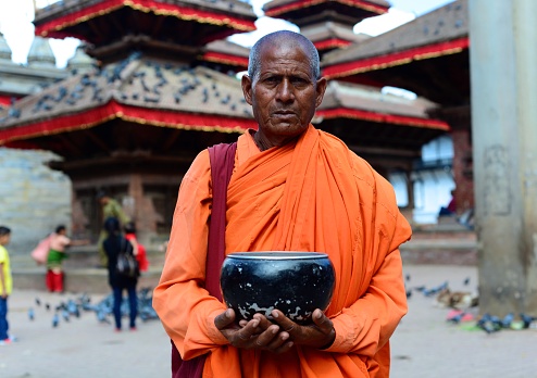 Kathmandu, Nepal - March 2, 2012: A monk begs for his alms in a temple