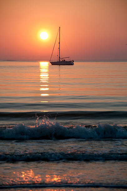 Sail boat sits motionless in the sunset