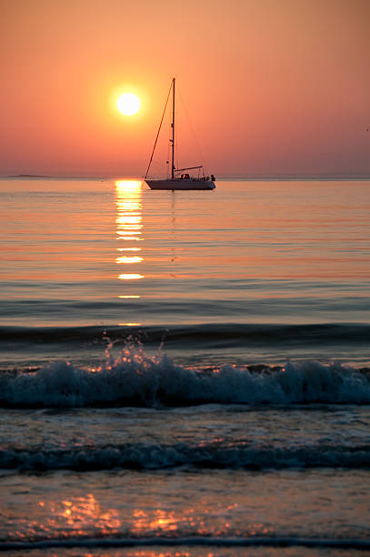 Sail boat sits motionless in the sunset stock photo
