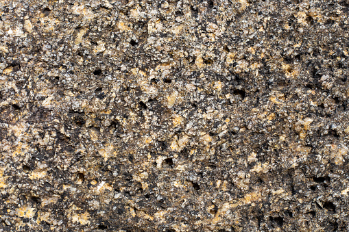 Rough stone texture. Stone mountain with an uneven surface, interspersed with small stones.