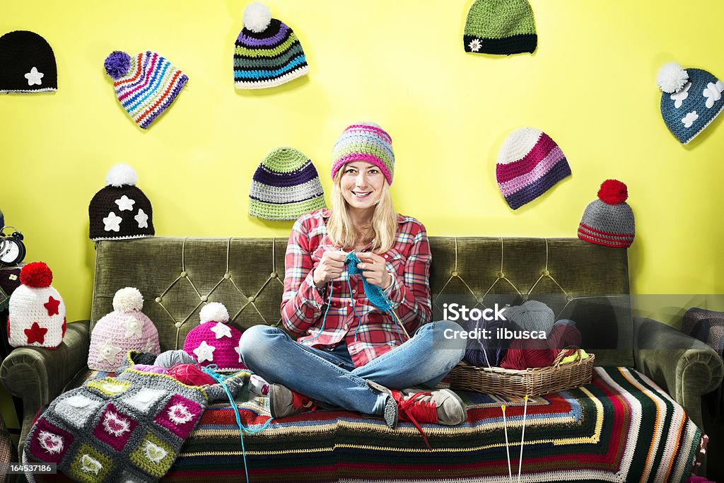 Bild einer strickenden, jungen Frau auf einer couch mit Wintermützen - Lizenzfrei Stricken Stock-Foto