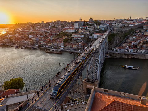 Aerial view cityscape over Douro river, Porto, Portugal. Metro train travelling across the Dom Luis I bridge and colorful buildings at the old district of Ribeira.