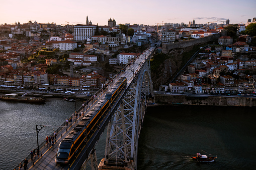 Aerial view cityscape over Douro river, Porto, Portugal. Metro train travelling across the Dom Luis I bridge and colorful buildings at the old district of Ribeira.