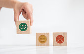 Woman hand hold wooden block with icon happy smiley face. Mental health assessment and medical concept.