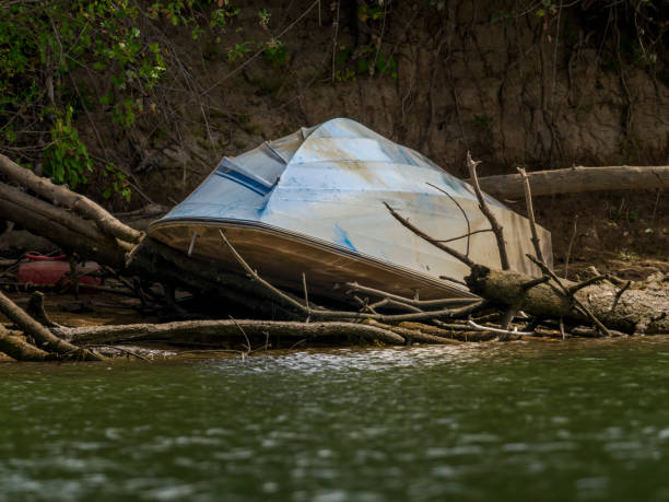 A derelict, small boat in Multnomah Channel along Sauvie Island Oregon. This is in the Portland, Oregon area. Abandoned boats are a problem in the rivers and expensive to remove. Photo taken from the river.