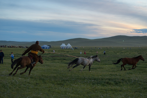 Bayan-Olgii Province, Mongolia - October 1, 2023: Teenager Aimuldir D. (middle), an ethnic Kazakh female eagle hunter and eventual winner of the Ulgii Golden Eagle Festival, rides horseback with family members at the end of the festival.