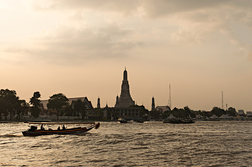 Both passing Wat Arun, The iconic tourist travel place in Bangkok, Thailand in the evening when the sunset. Wat Arun is the beautiful temple there is the stupa that is the destination for travel.