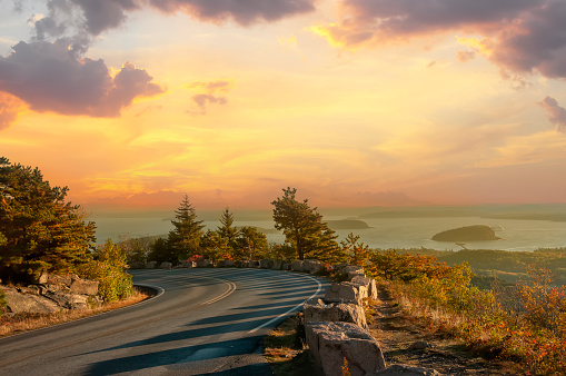 Road on the slopes of the mountains overlooking the bay of the Atlantic Ocean and the islands in the sunset light. Acadia National Park. USA