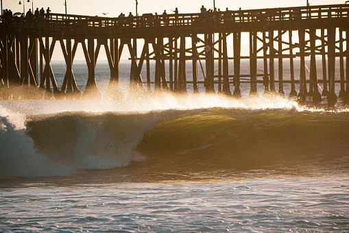 a wave breaks left, right in front of Ventura's pier