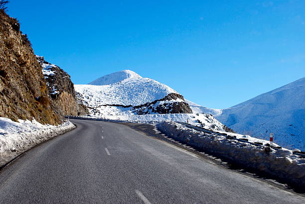 A road, the Great Alpine Highway, leads through the snow into the beginning of the Southern Alps, New Zealand.