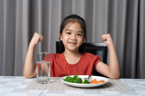 Kid shows strength of eats vegetables and nutritious food. stock photo