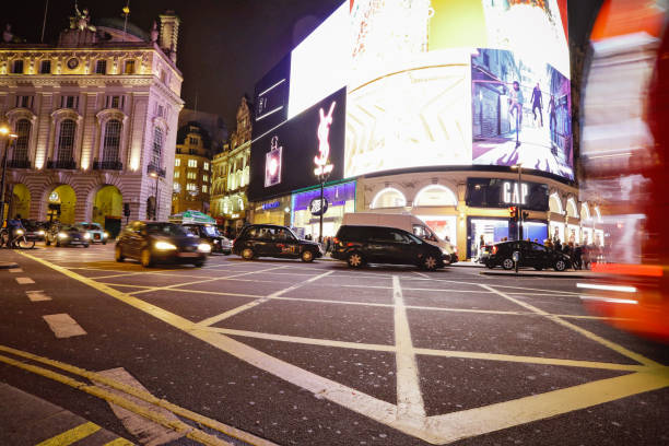 London, UK - Mar 12, 2019: Piccadilly Circus as people explore the shopping district and Black Cabs and Red Double Decker buses pass early in the night.