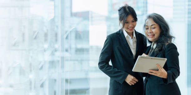 young financial assistant working on tablet and senior professional giving advise