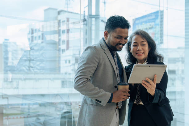 istock Two happy diverse coworker discussing report on tablet, working on project together 1645600935
