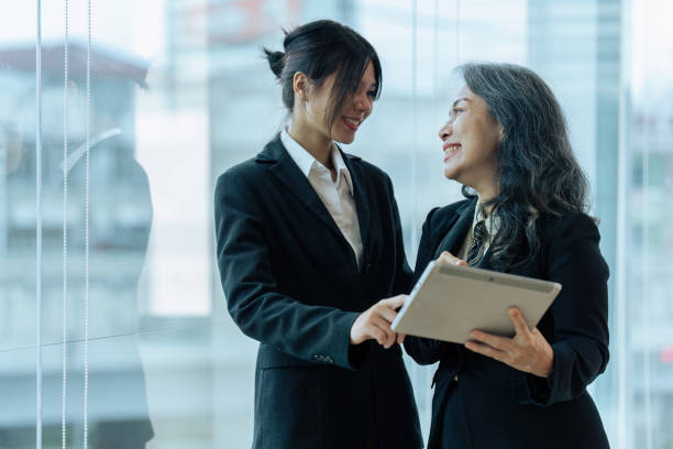 istock Two happy diverse coworker discussing report financial on tablet, working on project together 1645600956