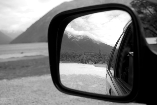 Looking at the view from a car mirror. The scenery surrounding is Nelson Lakes National Park, New Zealand in blur. Selective focus on the view in the reflection.
