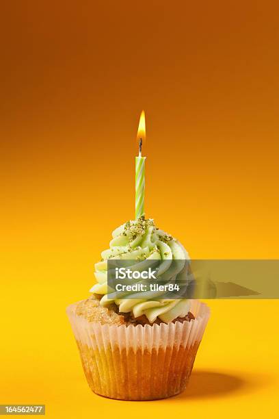 Foto de Cupcake Com Vela Isolada Em Fundo Laranja e mais fotos de stock de Fundo laranja - Fundo laranja, Bolinho, Chama