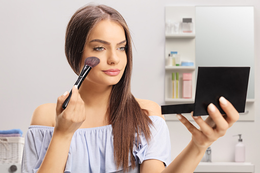 Young woman using a make-up brush in a bathroom
