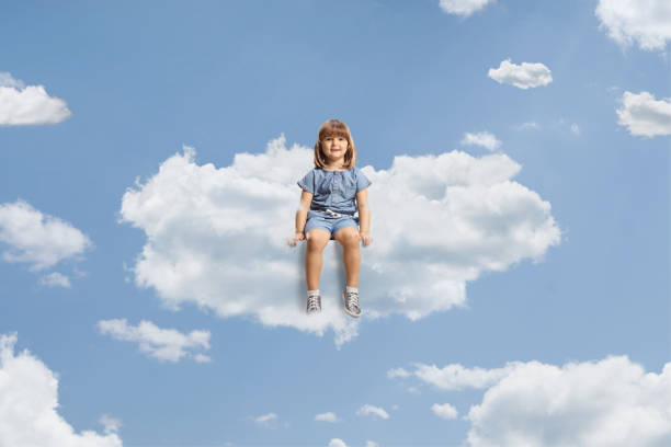 Little girl sitting on a cloud and smiling up in the sky