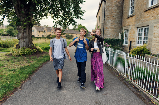 Three teenage kids enjoying summer vacations in Gloucestershire, United Kingdom. \nThey are walking in the beautiful village of Lower Slaughter. The River Eye is flowing in the center of the village.\nShot with Canon R5