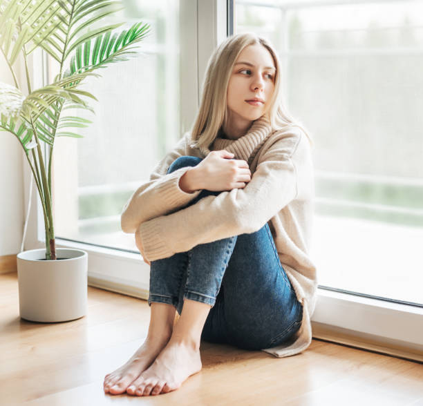 istock Sad girl near window thinking about something 1645754789