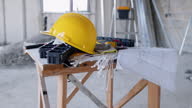 istock Construction site with yellow hardhat, work tools, architectural plan on the table and ladder 1645764630