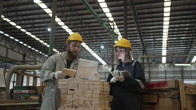 Blue collar workers are working at wooden pallets factory.