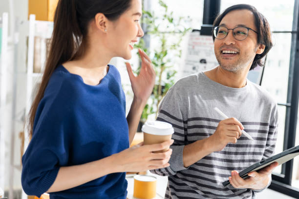 istock Two creative asian people sharing ideas and discussing about  mobile app interface design  at creative office. 1645786042