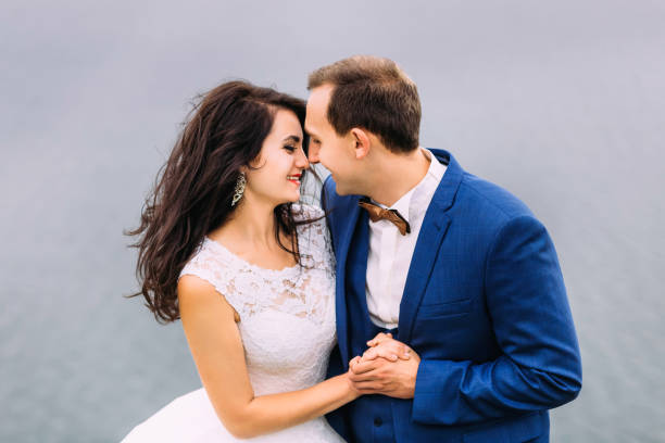 Nice wedding couple holding their hands and laughing at each other. Tenderly kissing couple.