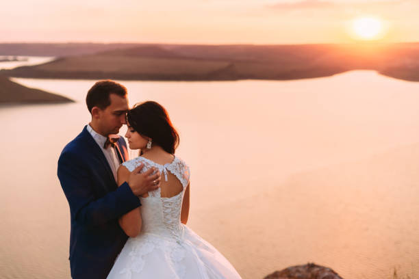 istock Wedding couple looking down and hugging romantically at sunset o 1645795623